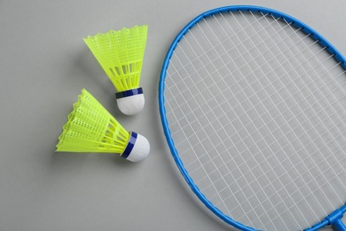 Badminton racket and shuttlecocks on grey background, flat lay