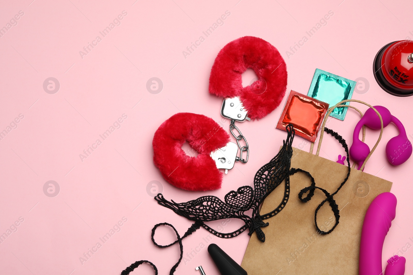 Photo of Shopping bag and different sex toys on pink background, flat lay. Space for text