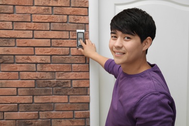 Young man scanning fingerprint on alarm system indoors