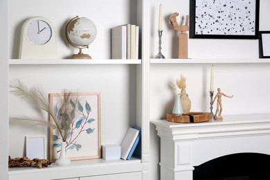 Photo of White shelves with books, globe and different decor indoors. Interior design