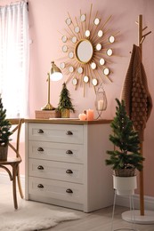 Photo of Stylish room interior with dresser and small fir trees