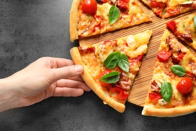 Photo of Man taking slice of delicious pizza with tomatoes and sausages at table