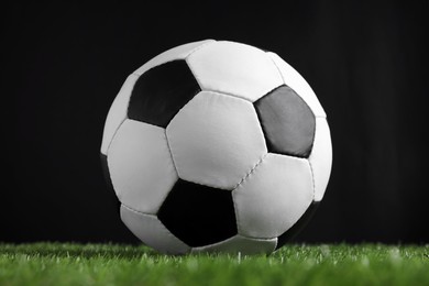 Photo of Football ball on green grass against black background