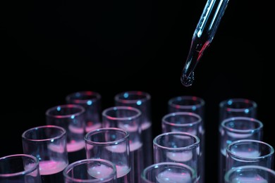 Photo of Dripping reagent into test tube on black background, closeup. Laboratory analysis