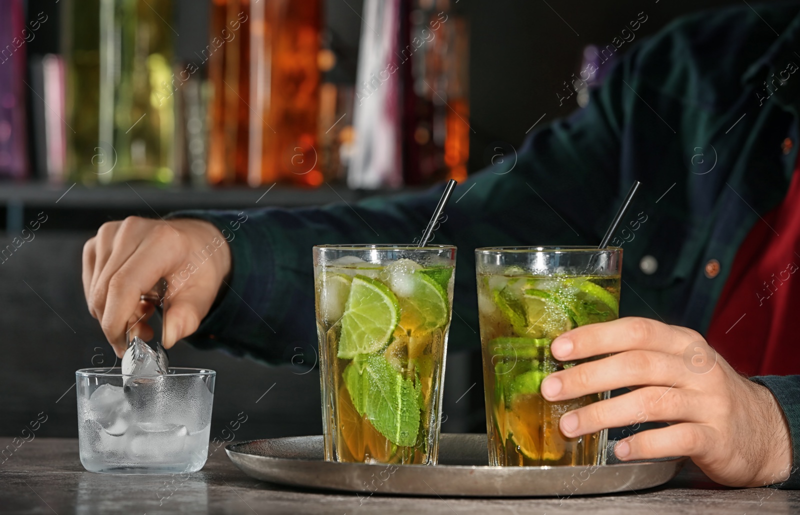 Photo of Bartender preparing delicious mint julep cocktail at table