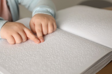 Photo of Blind child reading book written in Braille, closeup.