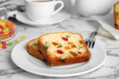 Photo of Delicious cake with candied fruits and tea on white marble table