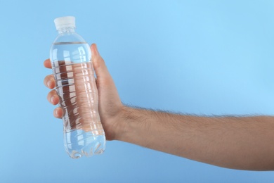 Photo of Man holding plastic bottle with water on color background