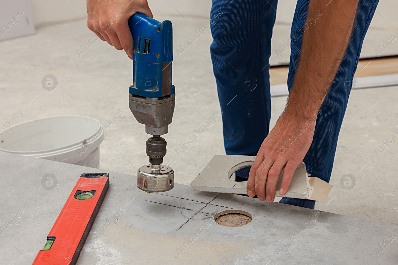 Photo of Worker making socket hole in tile indoors, closeup