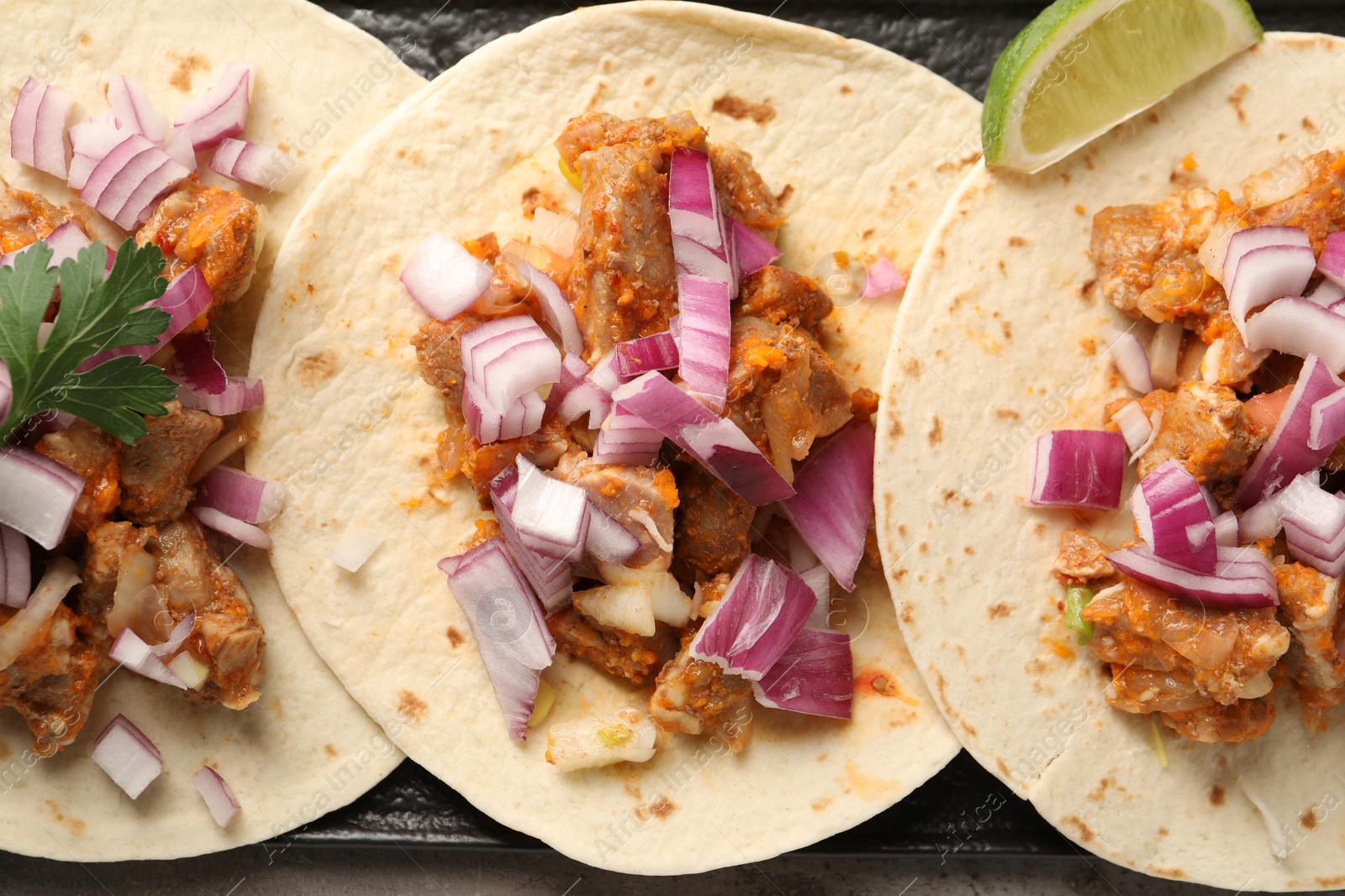 Photo of Delicious tacos with vegetables, meat and lime on table, flat lay