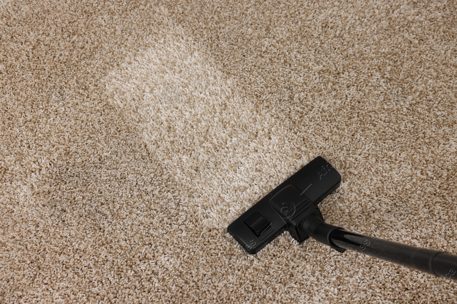 Photo of Hoovering carpet with vacuum cleaner, top view. Space for text