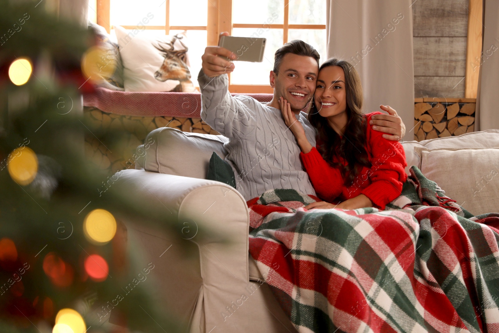 Photo of Happy young couple taking selfie in living room decorated for Christmas