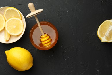 Photo of Sweet honey and fresh lemons on black table, flat lay. Space for text