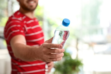 Photo of Young man with bottle of water at home, closeup
