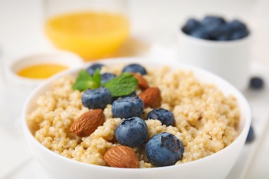 Photo of Bowl of delicious cooked quinoa with almonds and blueberries, closeup