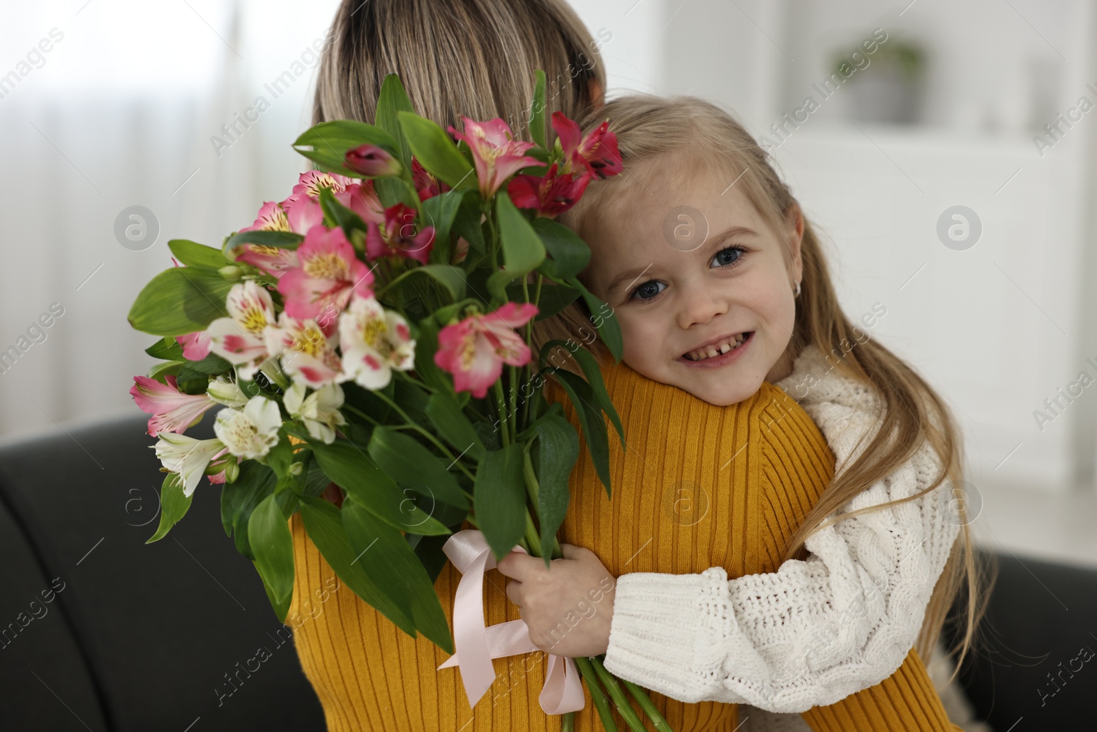 Photo of Little daughter congratulating her mom with bouquet of alstroemeria flowers at home. Happy Mother's Day