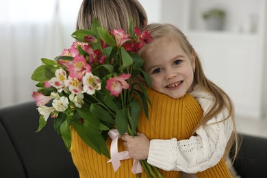 Little daughter congratulating her mom with bouquet of alstroemeria flowers at home. Happy Mother's Day