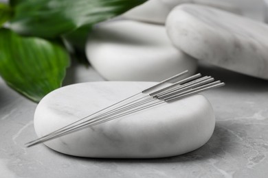 Photo of Stones with acupuncture needles on light grey marble table