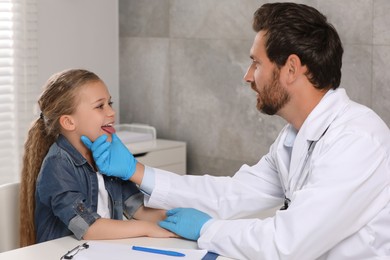 Photo of Doctor in medical gloves examining girl`s oral cavity indoors
