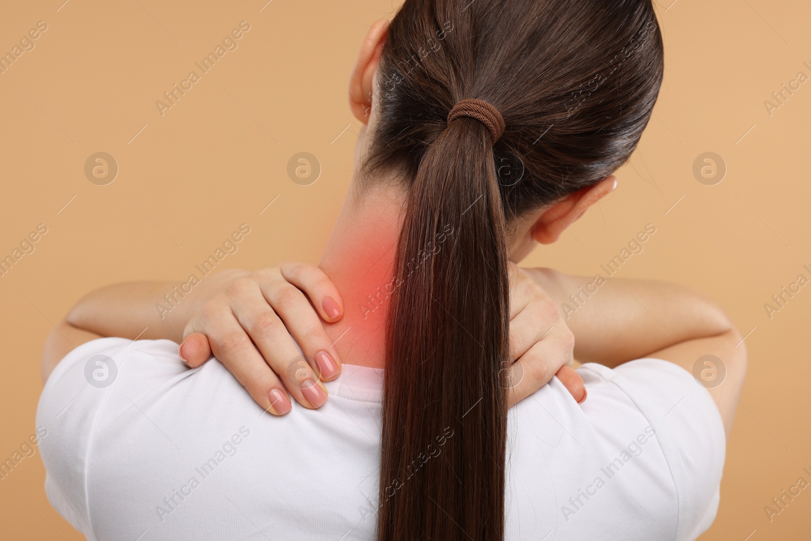 Image of Woman suffering from neck pain on dark beige background, back view