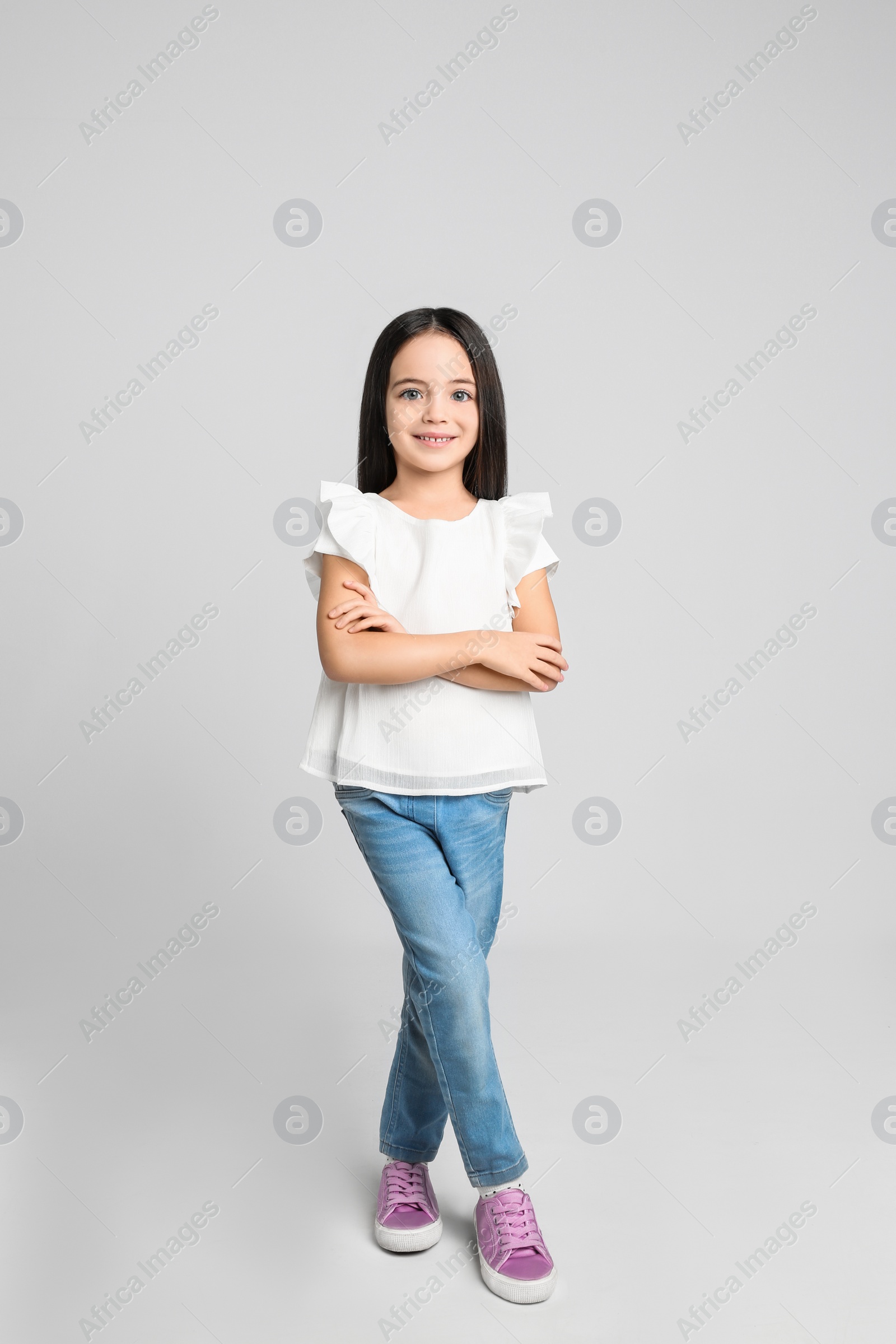 Photo of Cute little girl posing on light grey background
