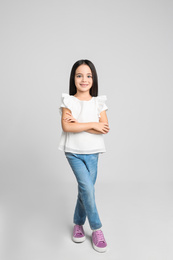 Cute little girl posing on light grey background