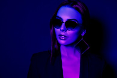 Beautiful woman wearing jacket and sunglasses in neon lights