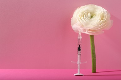 Photo of Cosmetology. Medical syringe and ranunculus flower on pink background, space for text