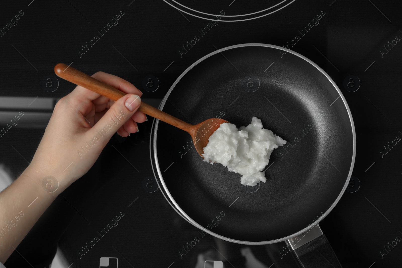 Photo of Woman cooking with coconut oil on induction stove, top view