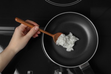 Photo of Woman cooking with coconut oil on induction stove, top view