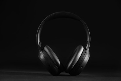 Photo of Modern wireless headphones on black background, closeup