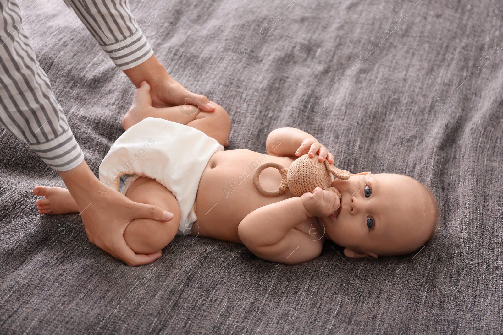 Photo of Young woman massaging cute little baby on blanket