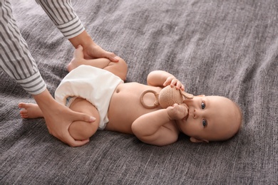 Young woman massaging cute little baby on blanket