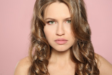 Portrait of beautiful young woman with shiny wavy hair on color background