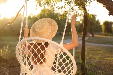 Photo of Young woman resting in hammock chair outdoors on sunny day. Summer vacation