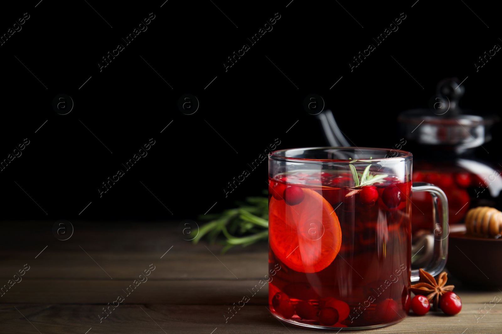 Photo of Tasty hot cranberry tea with rosemary and lemon on wooden table. Space for text