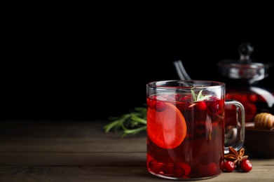 Photo of Tasty hot cranberry tea with rosemary and lemon on wooden table. Space for text