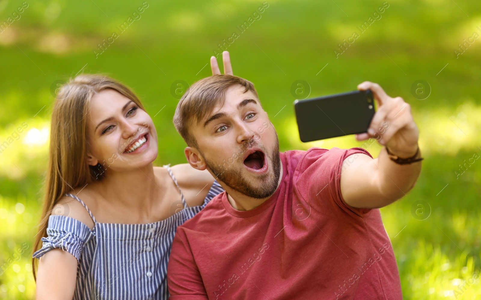 Photo of Happy young couple taking selfie on green grass in park