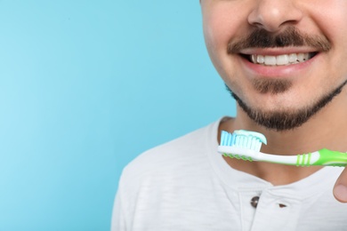 Photo of Young man brushing teeth on color background, closeup. Space for text