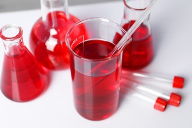 Photo of Laboratory analysis. Different glassware with red liquid on table indoors, closeup