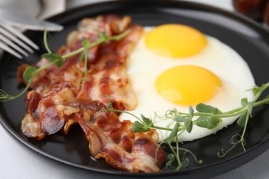 Fried eggs, bacon and microgreens on table, closeup