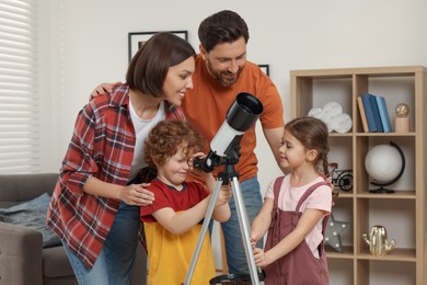 Happy family looking at stars through telescope in room