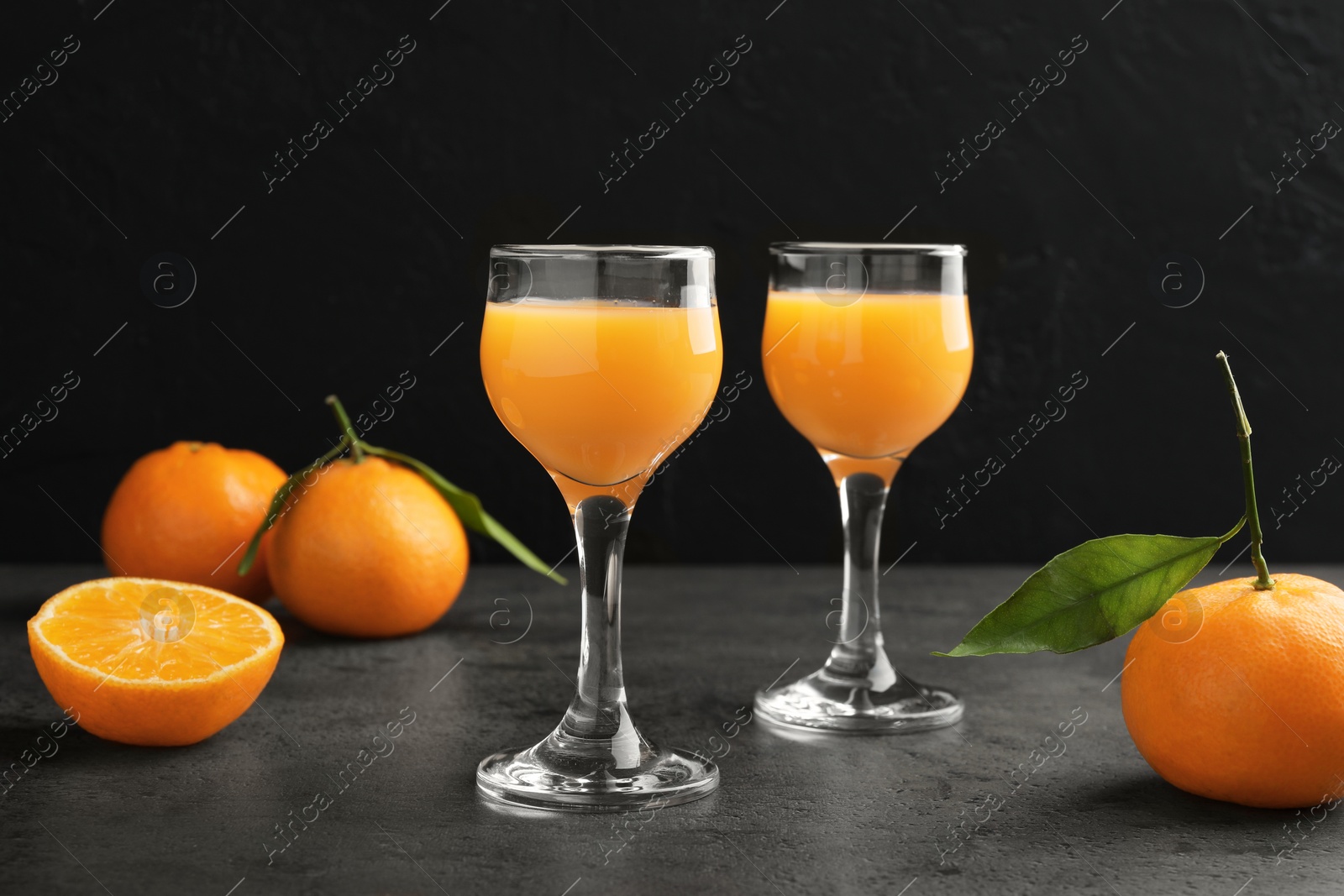 Photo of Delicious tangerine liqueur and fresh fruits on grey table