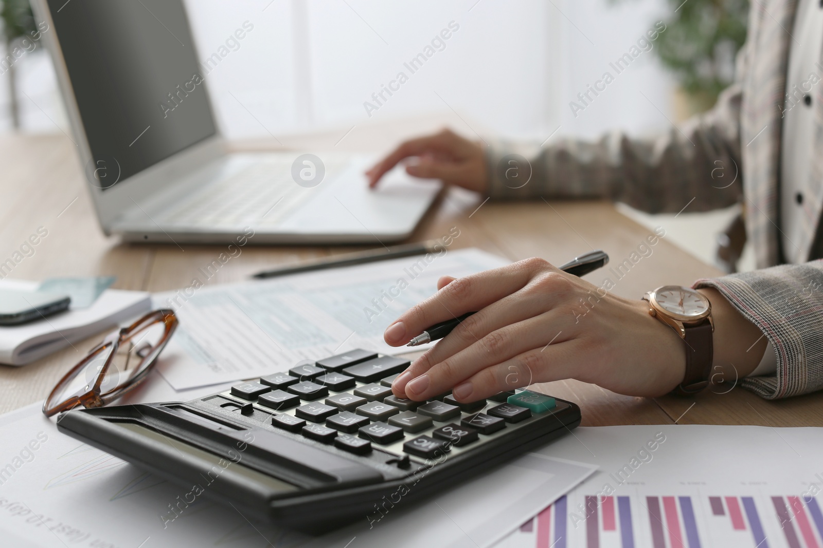 Photo of Tax accountant with calculator working at table in office, closeup