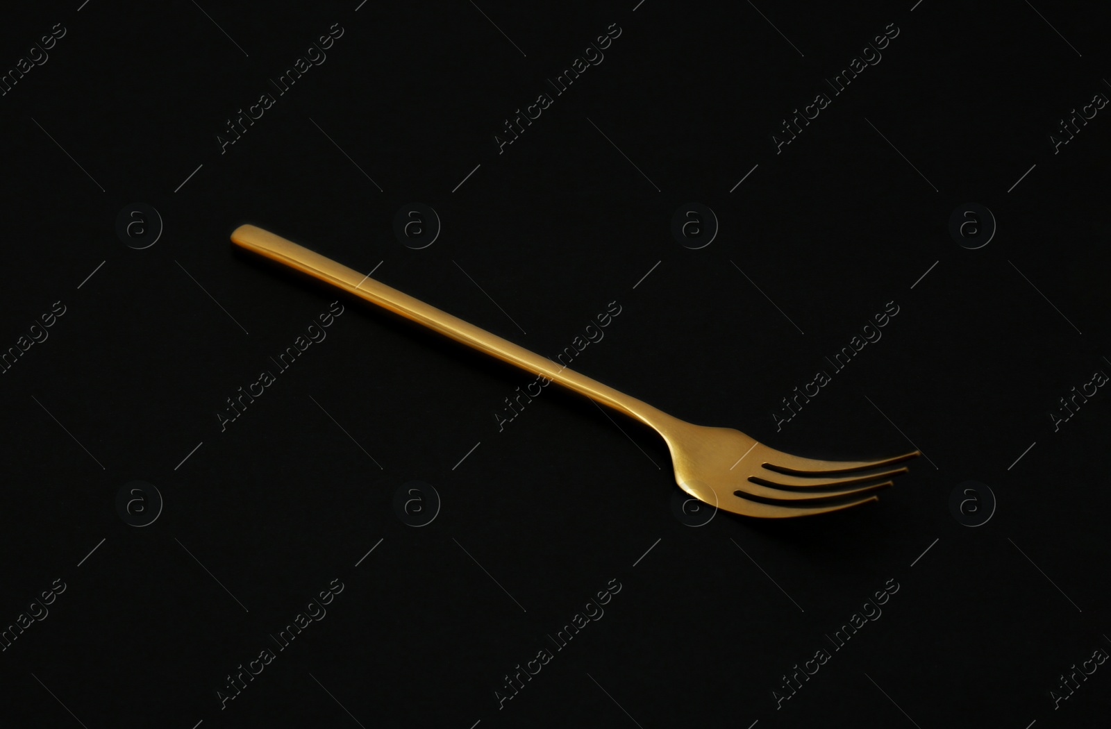 Photo of Shiny elegant gold fork on black background