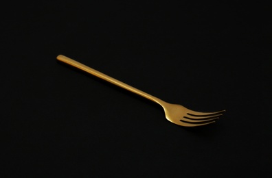 Photo of Shiny elegant gold fork on black background