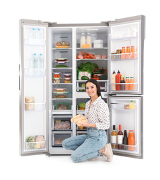 Photo of Young woman with corn near open refrigerator on white background