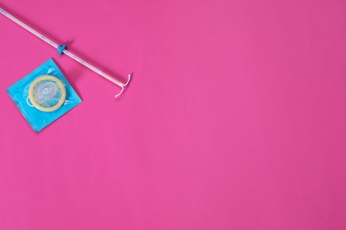 Photo of Contraception choice. Condoms and intrauterine device on magenta background, flat lay. Space for text