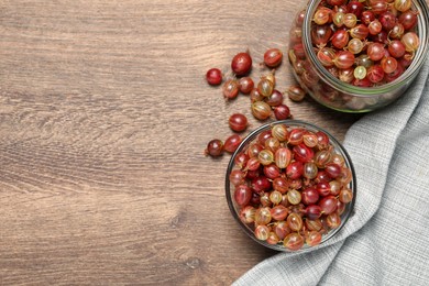 Photo of Many fresh ripe gooseberries on wooden table, flat lay. Space for text