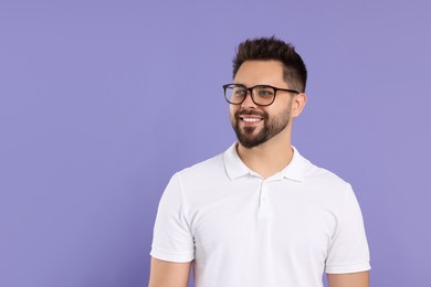 Handsome man wearing glasses on violet background, space for text